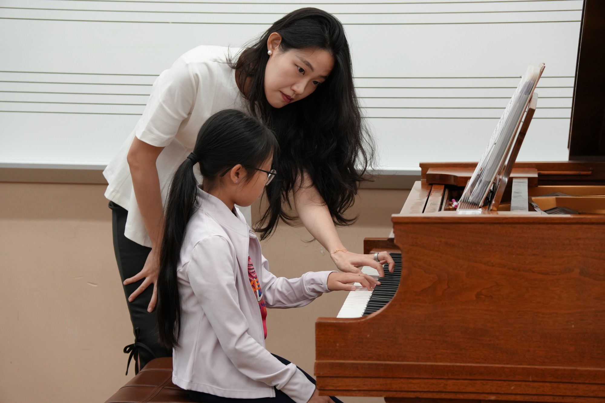 A faculty pianist guides a young student at the keyboard
