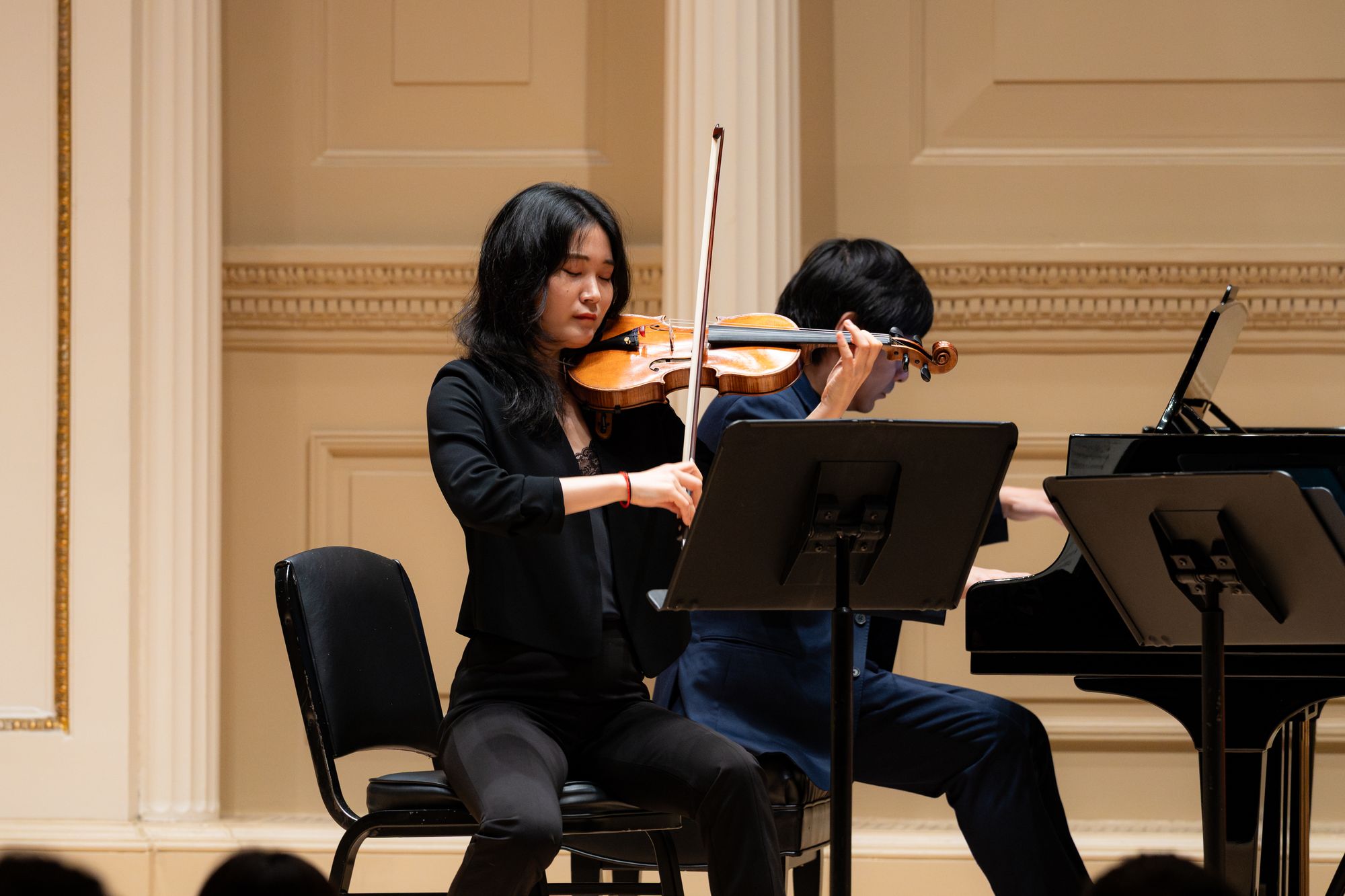 A faculty violinist and student rehearse together on stage