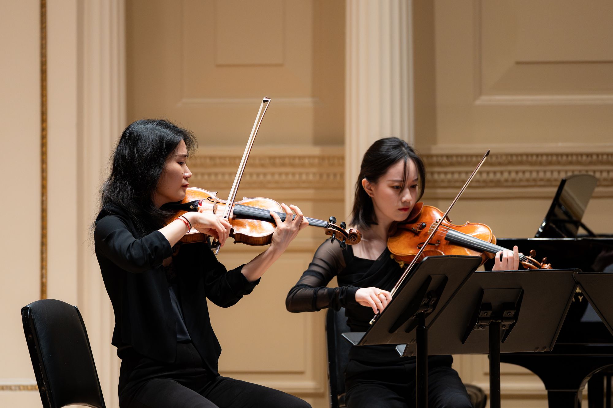 A faculty violinist plays alongside a student on stage