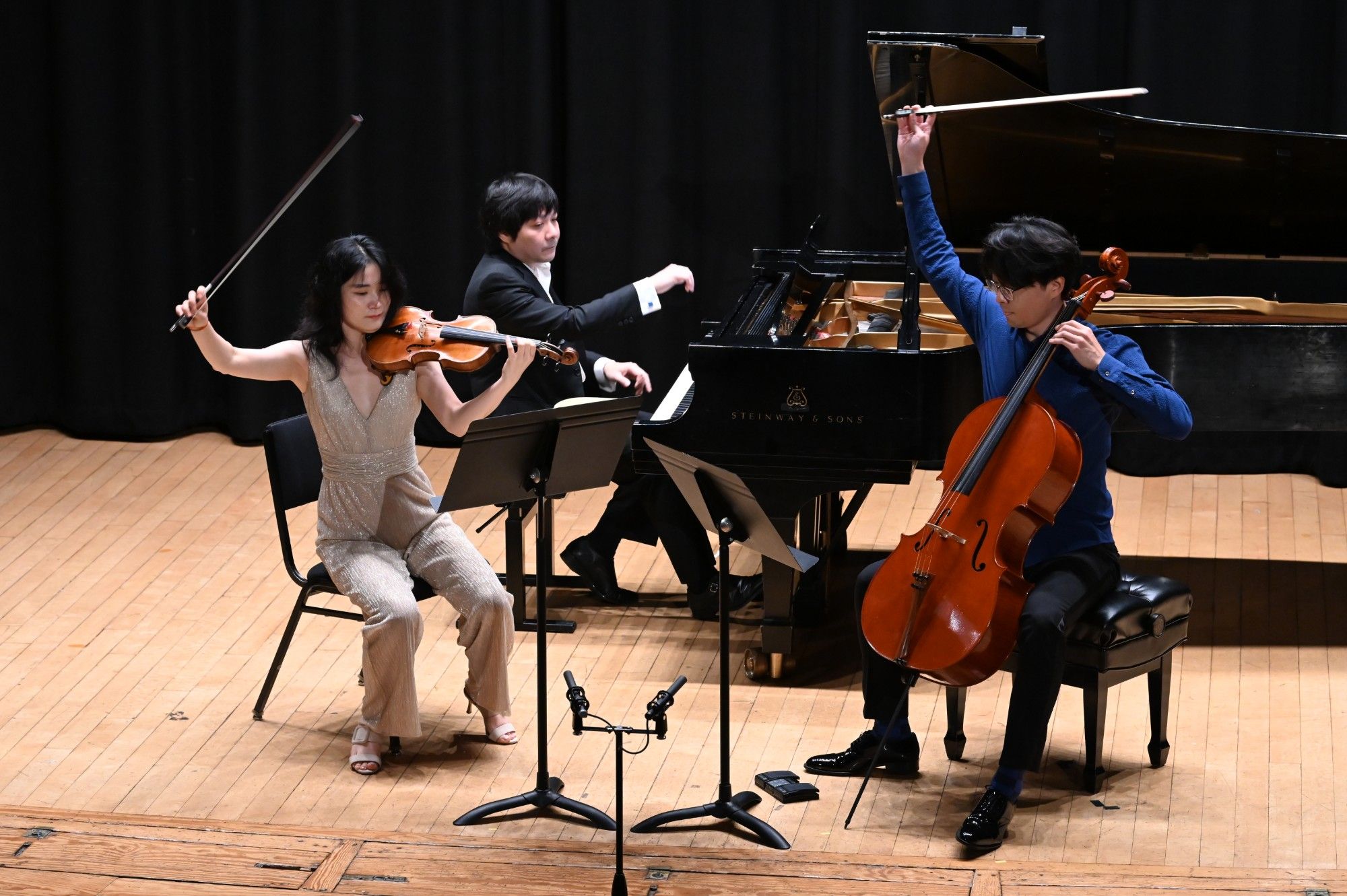Qianwen Shen, Yinfei Wang, and Mo Mo lift their bows at the close of a phrase