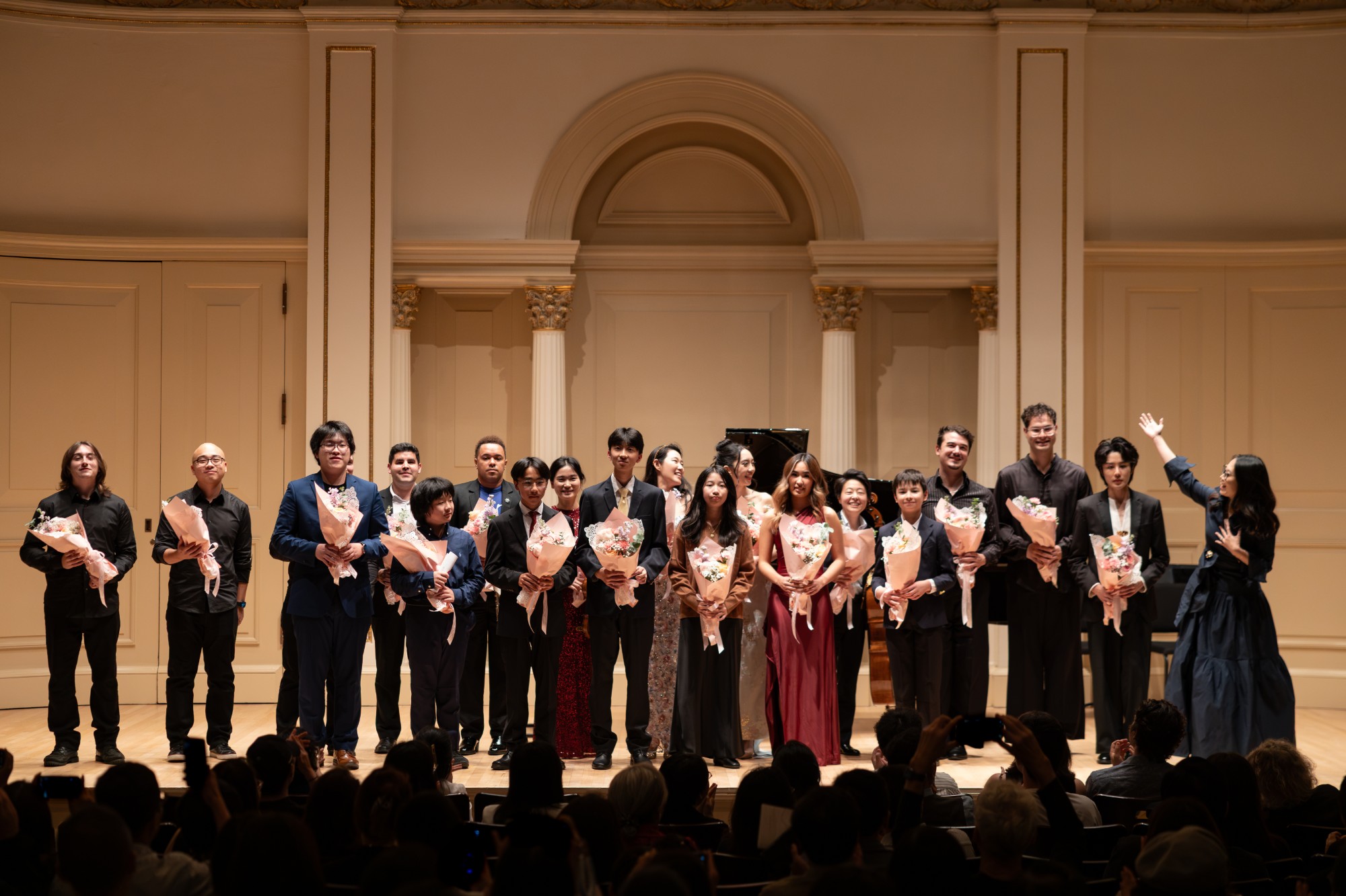 Young composers and performers hold bouquets on stage at the close of Voices Unbound