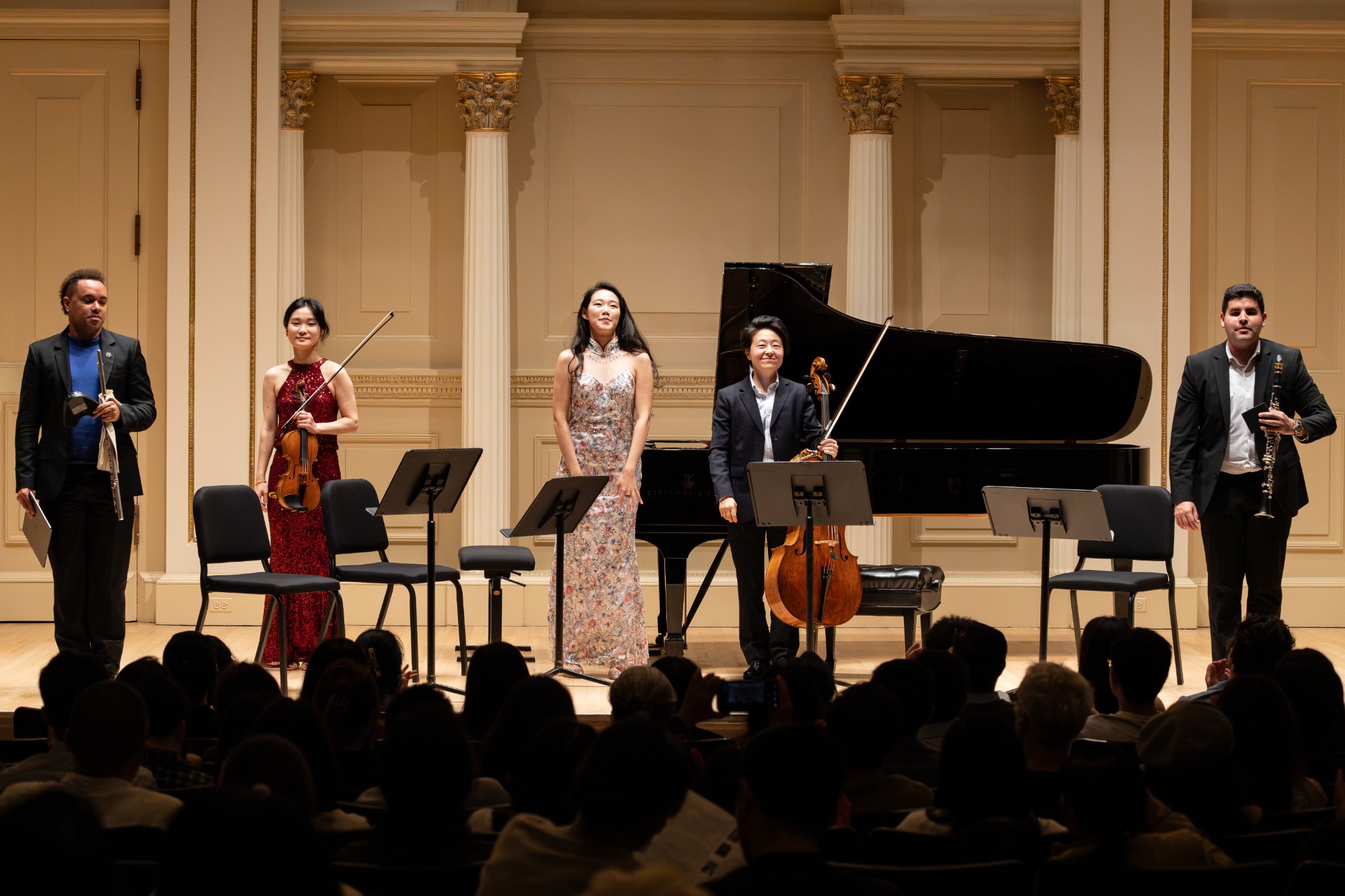 The quintet smiles as the audience applauds