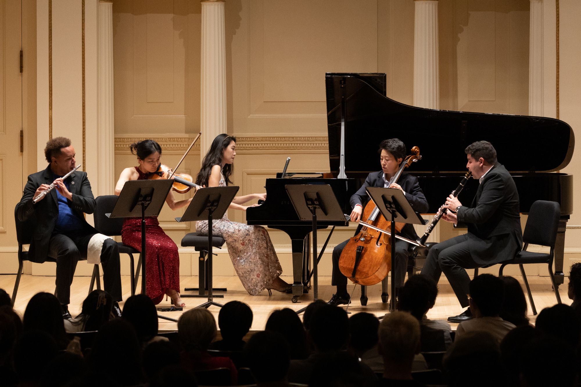 Flute, violin, piano, cello, and clarinet play together under the stage lights