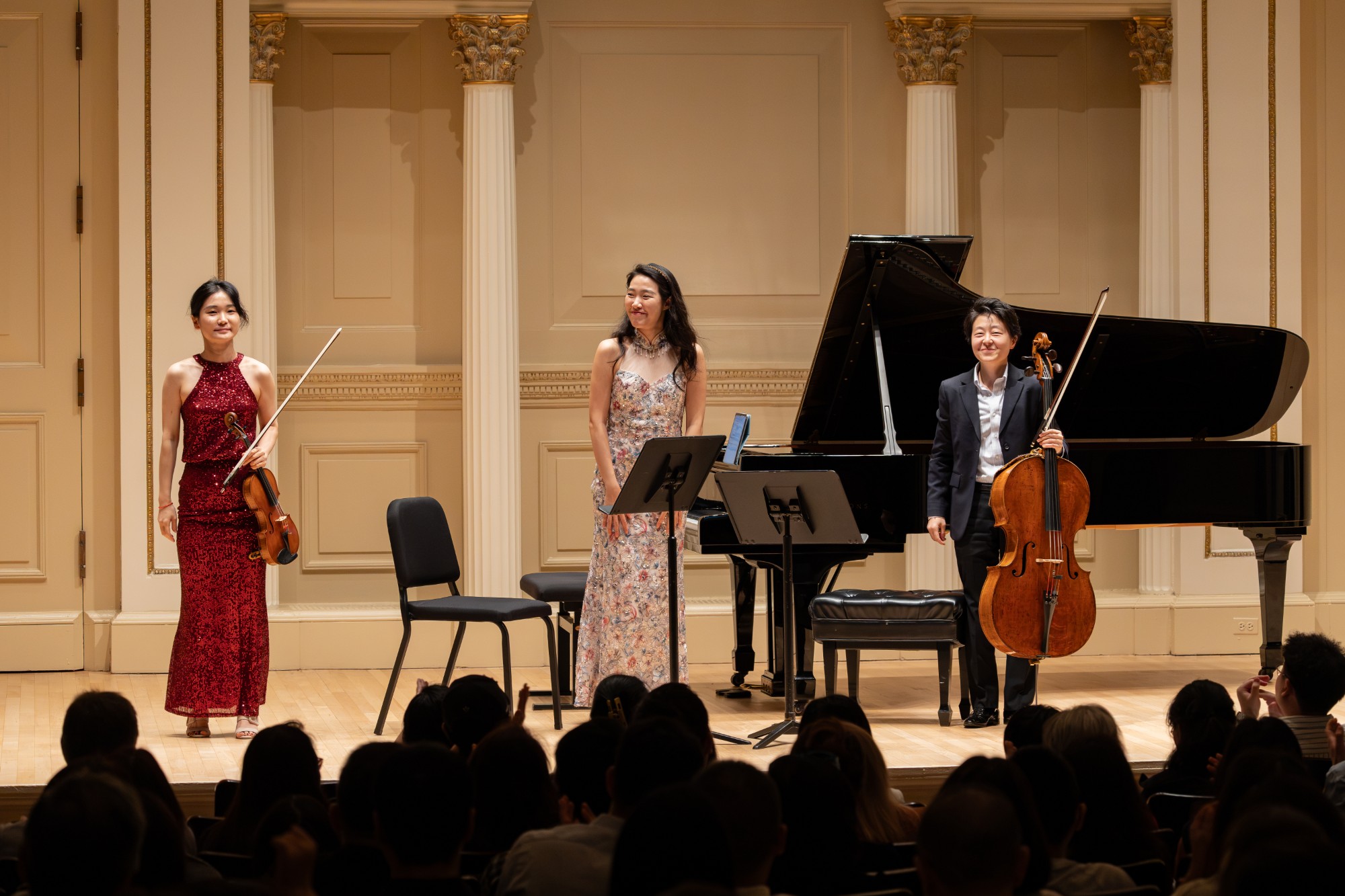 The piano trio smiles as the audience applauds
