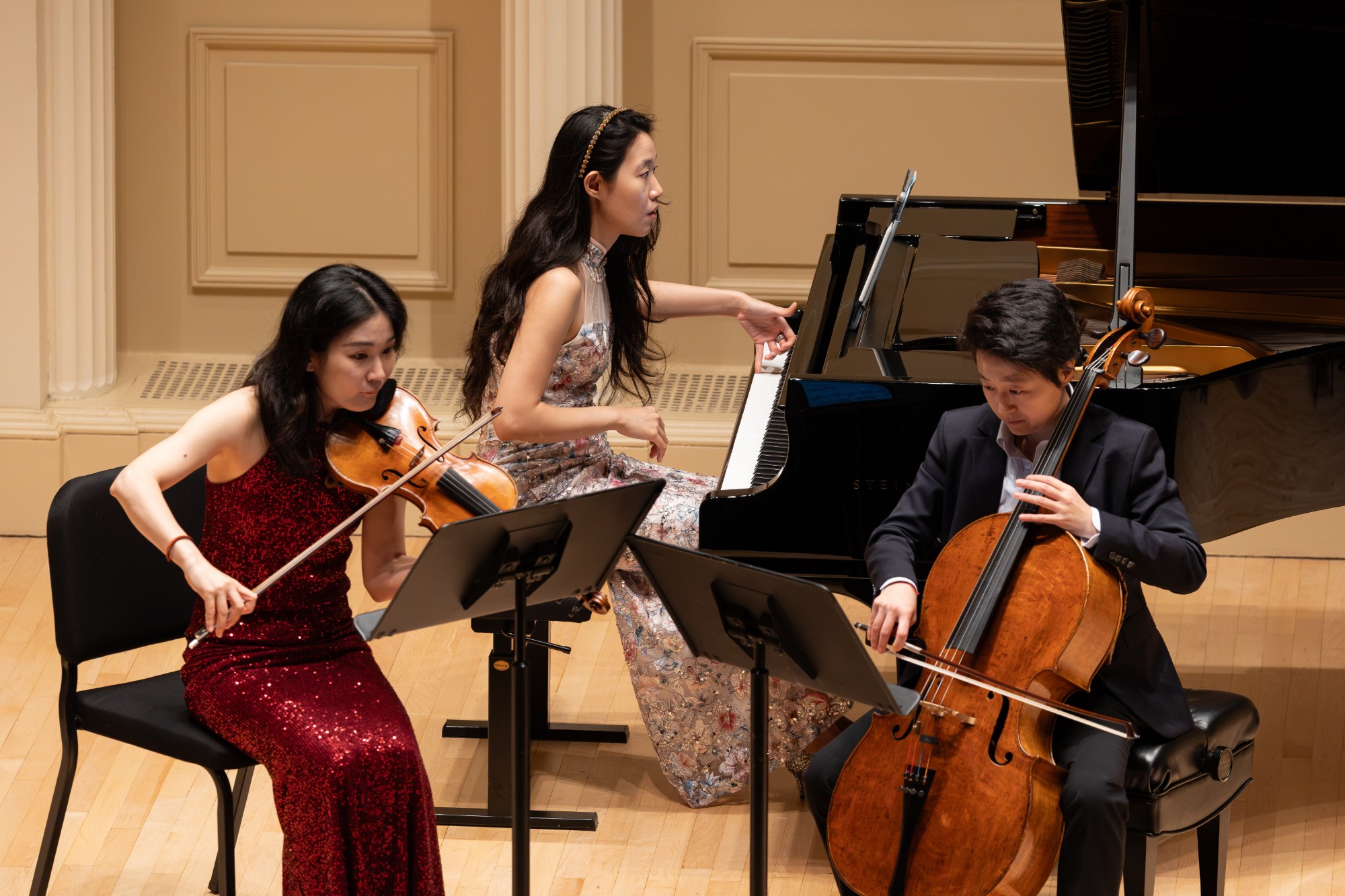 Violinist, pianist, and cellist play together in a close-up from the stage