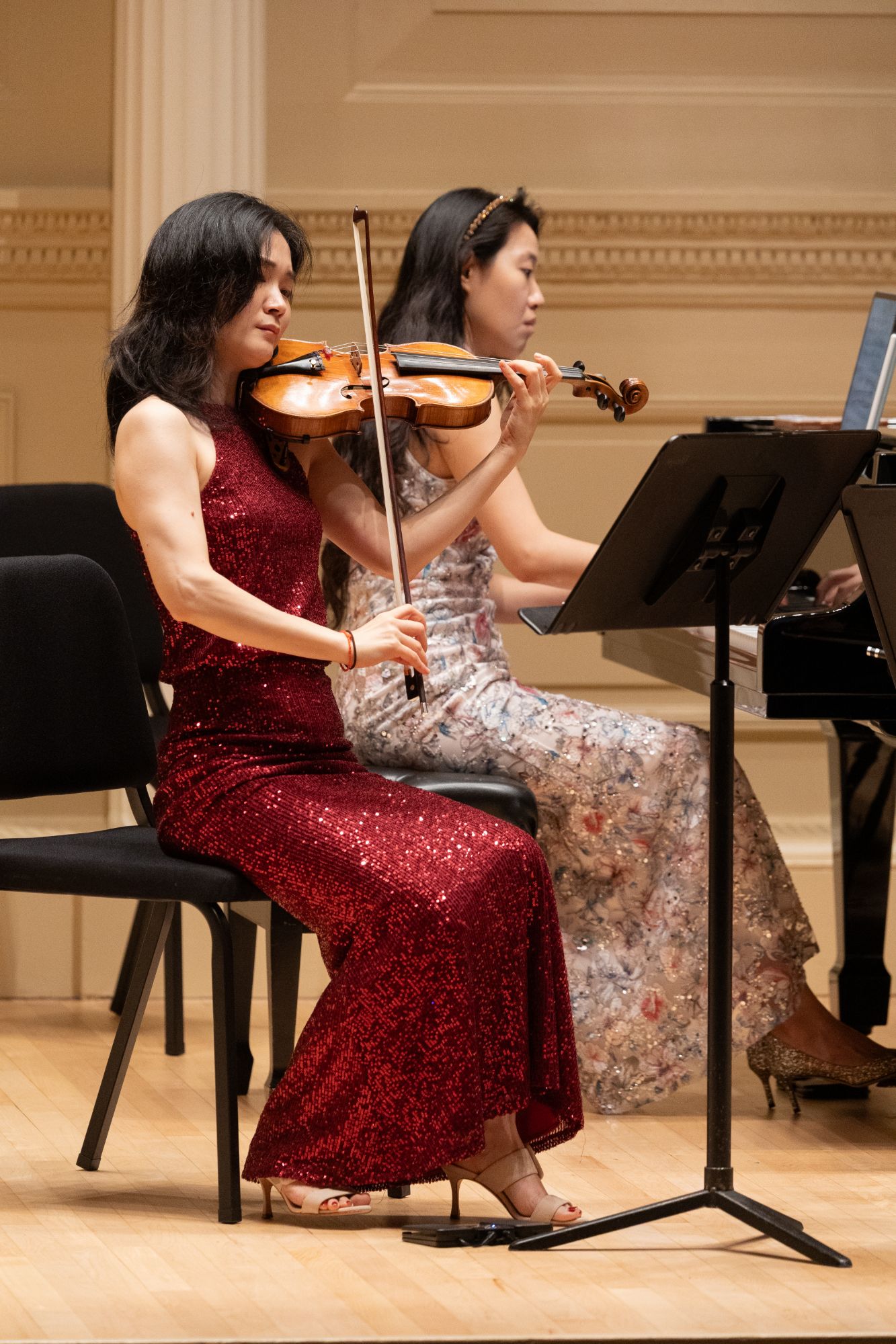 The violinist plays as the pianist follows at the keyboard